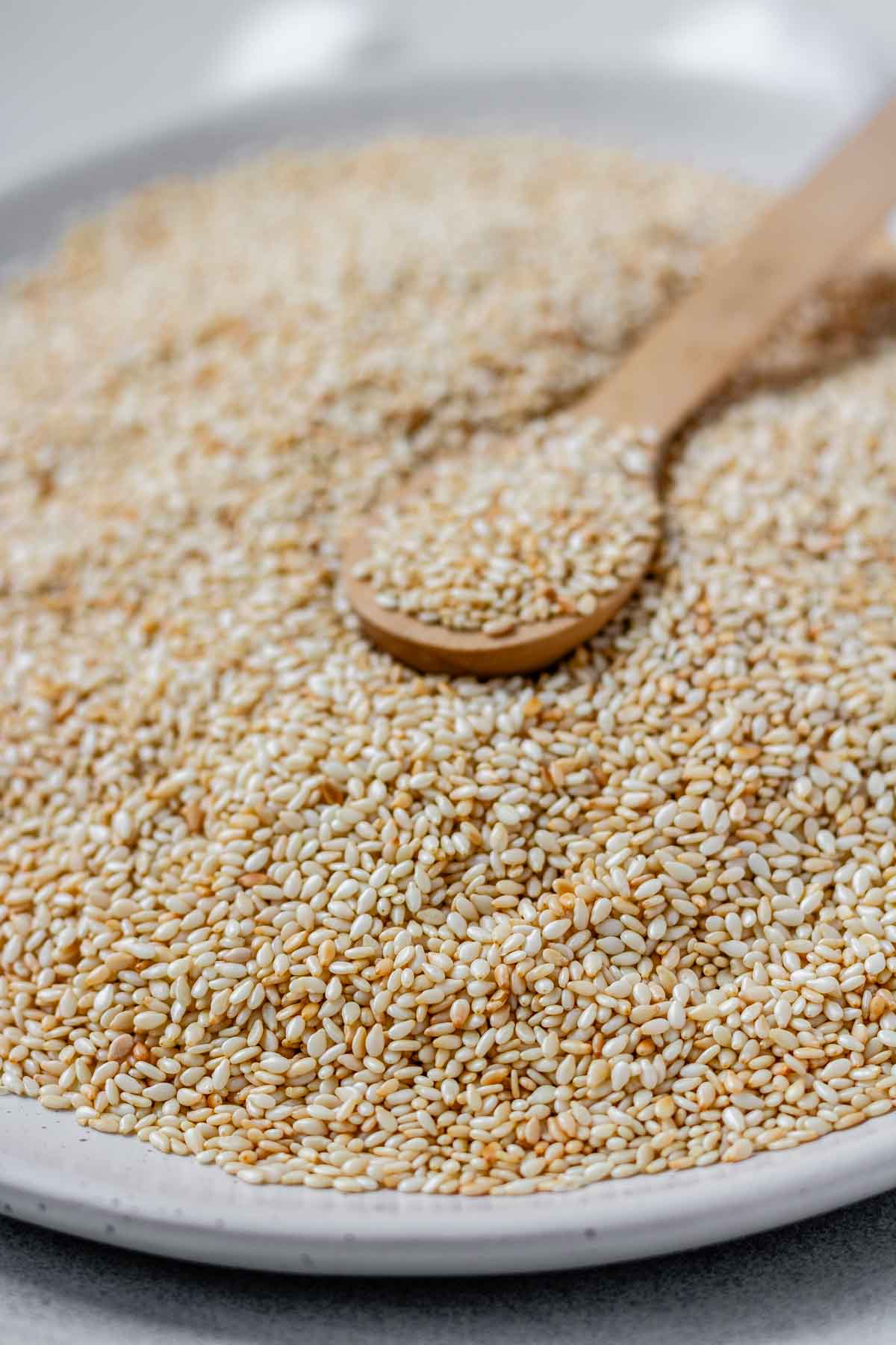 Golden toasted sesame seeds cooling on a plate.