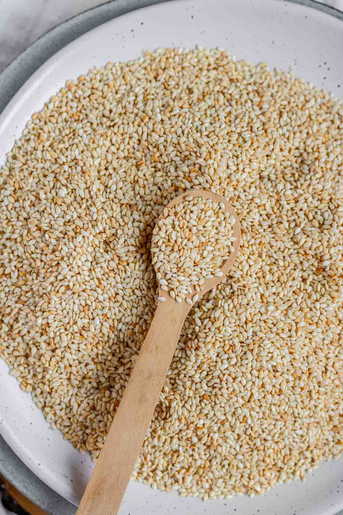Golden toasted sesame seeds cooling on a plate.