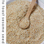 Golden toasted sesame seeds are cooling on a plate with the text How to toast sesame seeds.