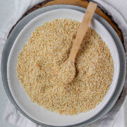 Golden toasted sesame seeds are cooling on a plate with the text How to toast sesame seeds.