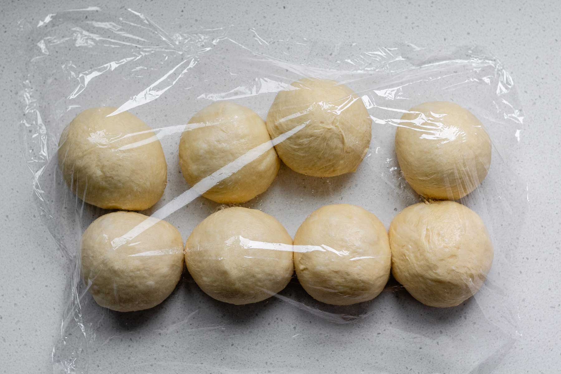 8 rounds of dough covered with plastic wrap.