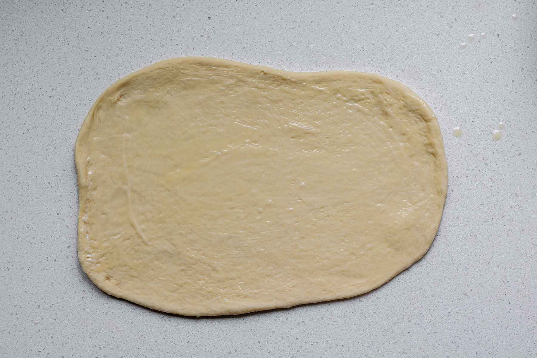 A rolled rectangle of dough covered with butter.