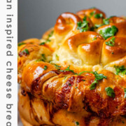 Rolled dough that has been baked and covered with parsley and butter with the text serbian inspired cheese bread.