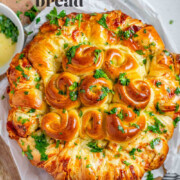 Rolled dough that has been baked and covered with parsley and butter with the text serbian inspired bread.