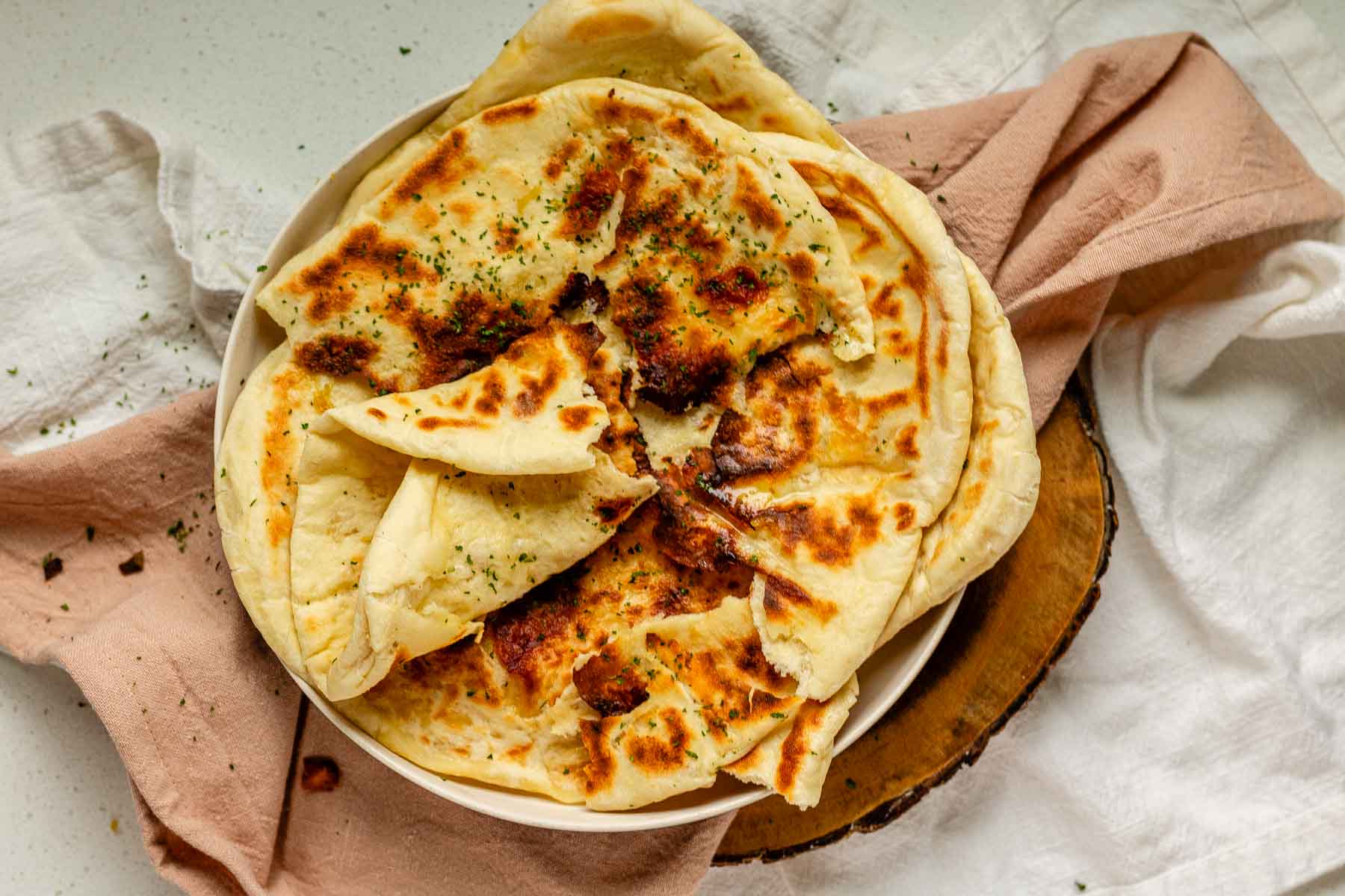 Homemade cheese naan stacked on a plate, soft and golden.