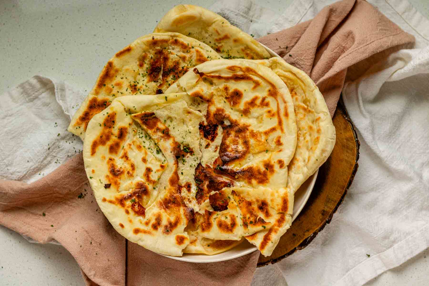 Homemade cheese naan stacked on a plate, soft and golden.
