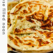 Homemade cheese naan stacked on a plate, soft and golden with the text cheese filled naan.