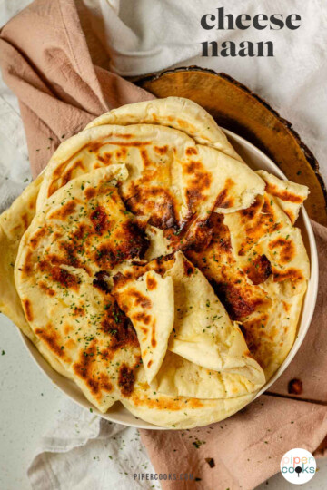 Homemade cheese naan stacked on a plate, soft and golden with the text cheese naan.