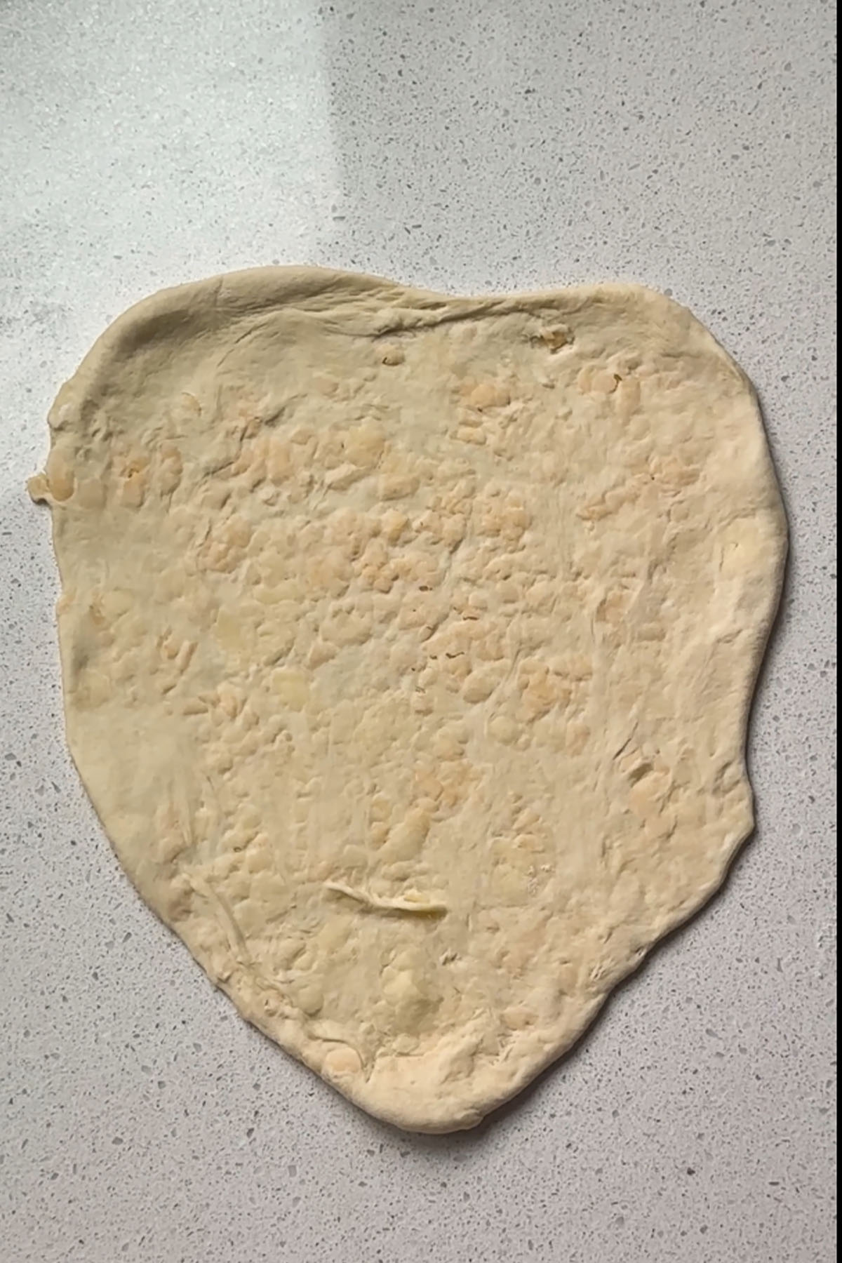 Rolled stuffed cheese naan dough before cooking.