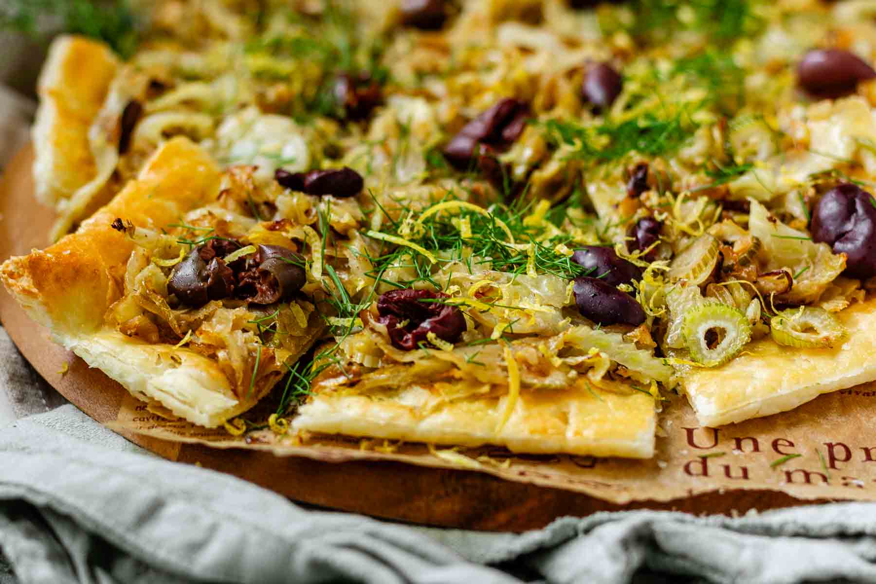 Baked puff pastry topped with fennel, onion, black olives, fresh dill, and lemon zest.