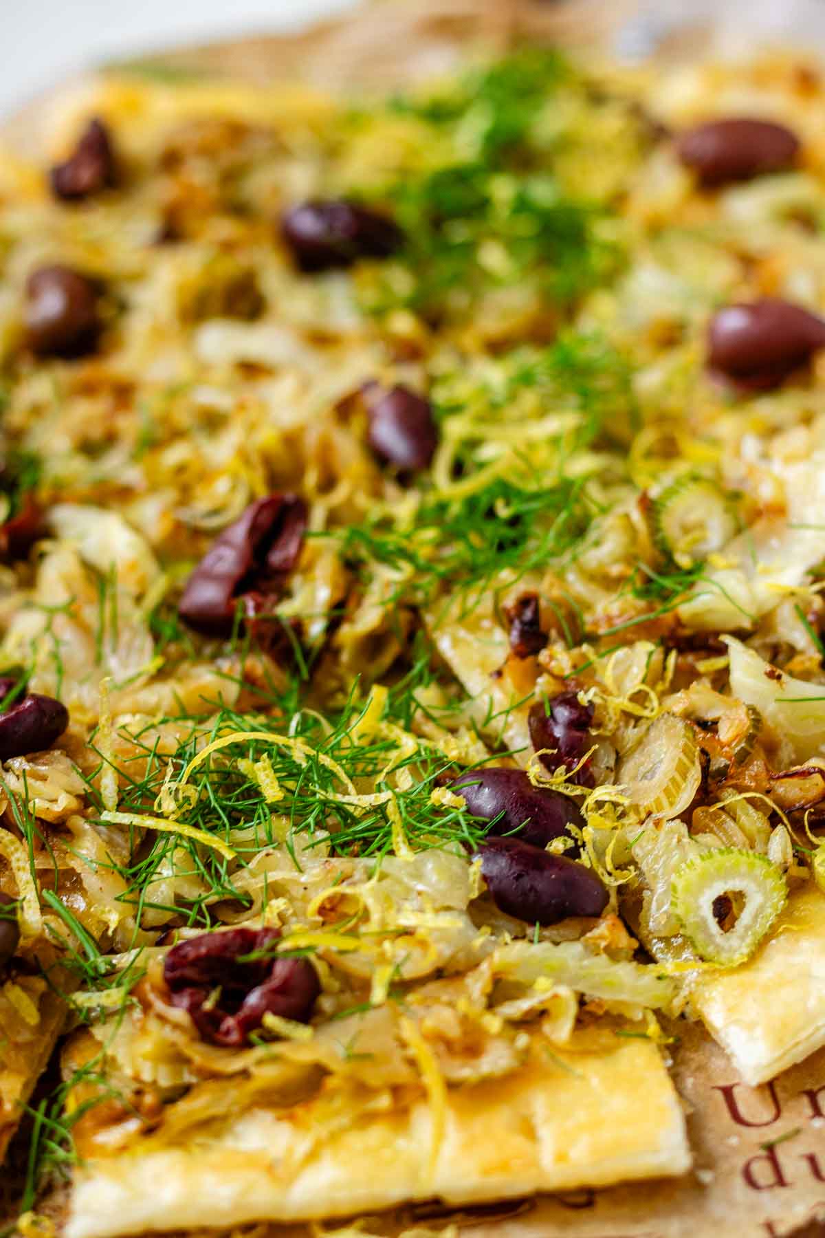 Baked puff pastry topped with fennel, onion, black olives, fresh dill, and lemon zest.
