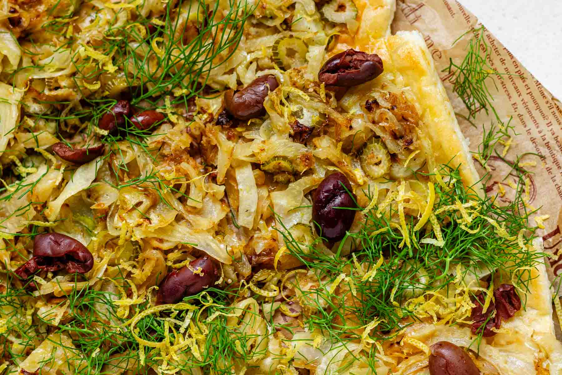 Baked puff pastry topped with fennel, onion, black olives, fresh dill, and lemon zest.