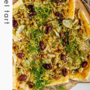 Baked puff pastry topped with fennel, onion, black olives, fresh dill, and lemon zest with the text fennel tart.