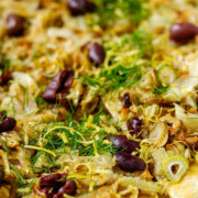 Baked puff pastry topped with fennel, onion, black olives, fresh dill, and lemon zest with the text fennel tart.