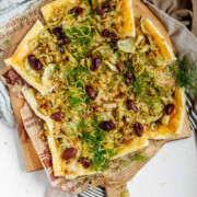 Baked puff pastry topped with fennel, onion, black olives, fresh dill, and lemon zest with the text fennel tart.