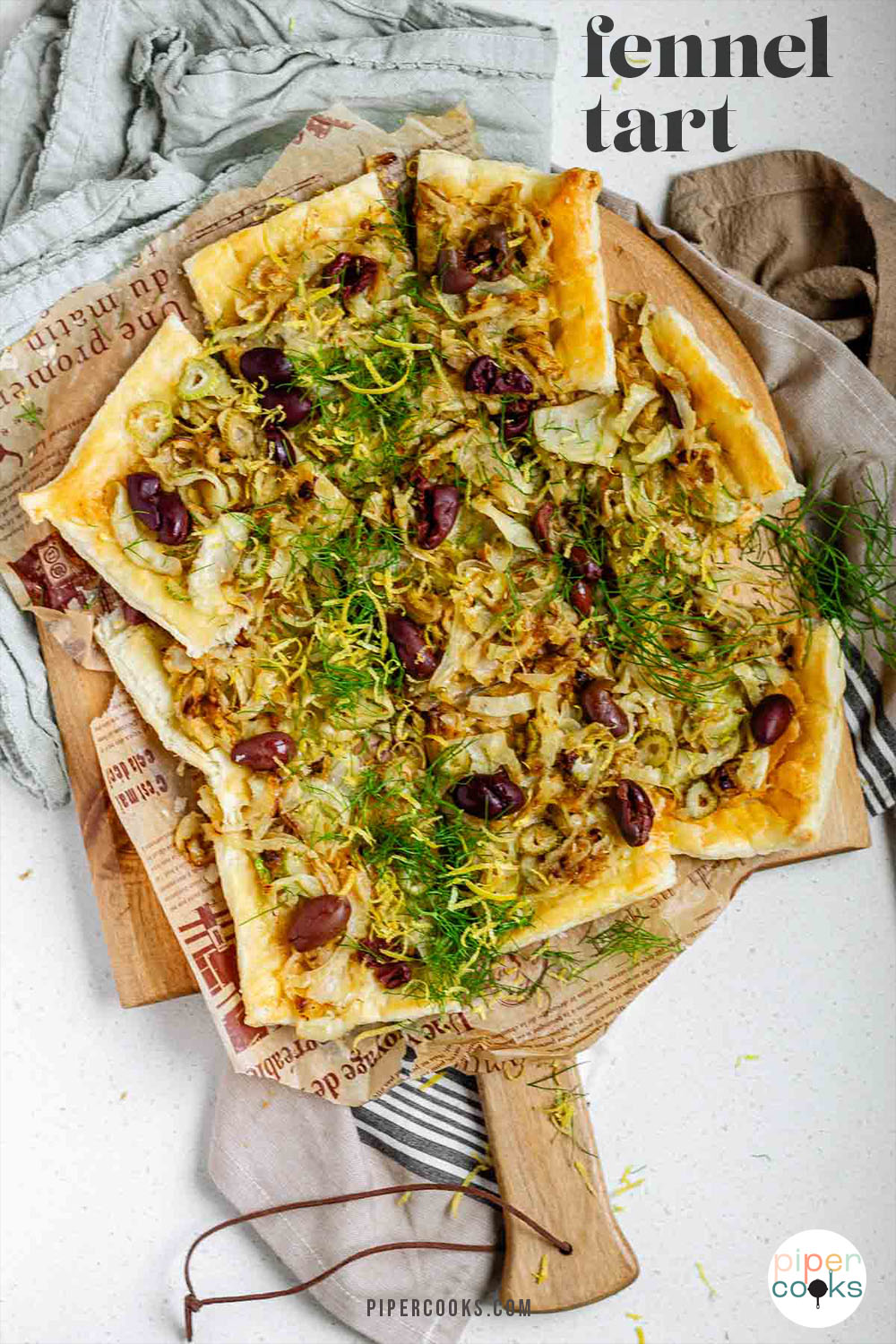 Baked puff pastry topped with fennel, onion, black olives, fresh dill, and lemon zest with the text fennel tart.