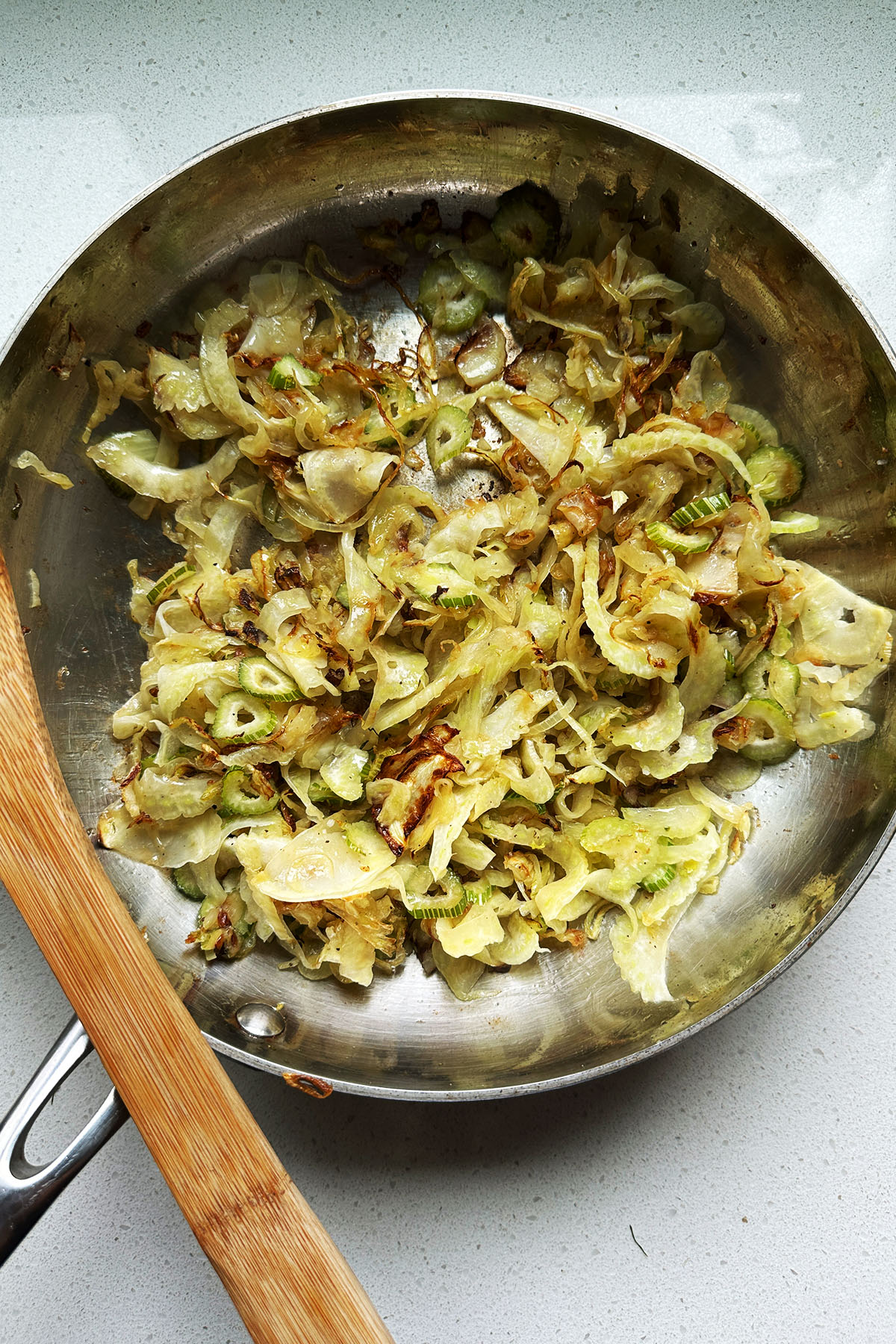 Cooked sliced fennel and onion in a skillet.