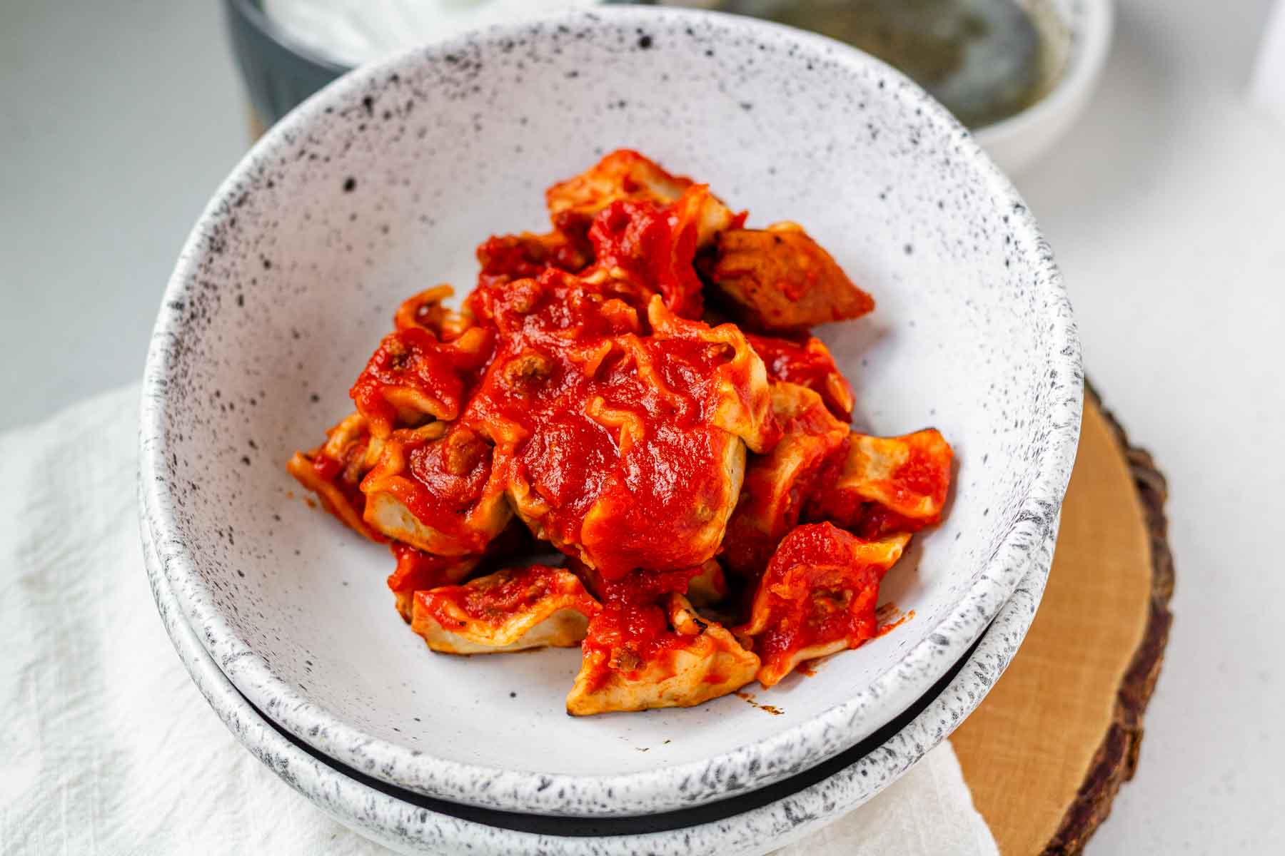 A bowl of dumplings in red sauce.