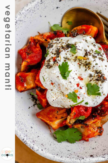 A bowl of dumplings in red sauce topped with yogurt and herbs with the text vegetarian manti.