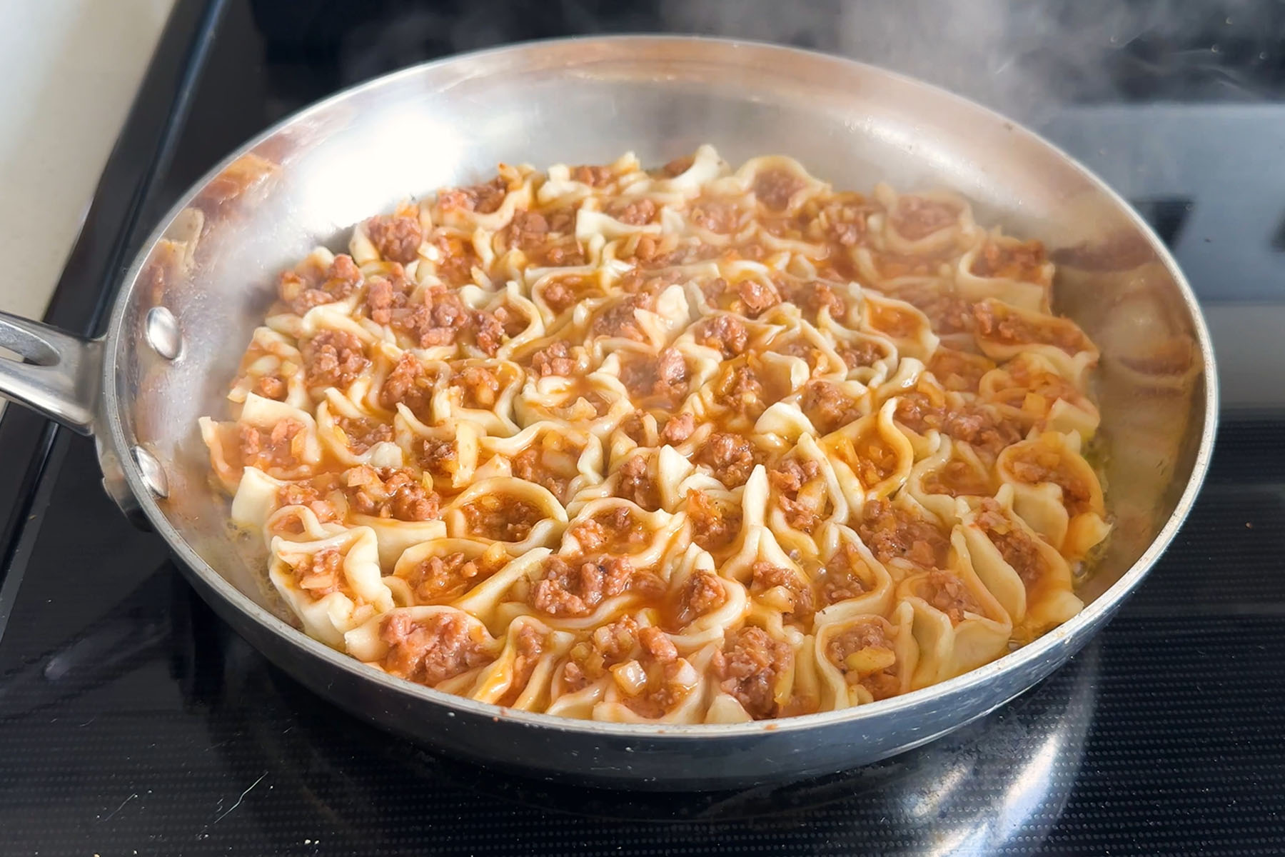 Dumplings filled with beyond beef arranged in a circle pattern in a skillet after they have steamed