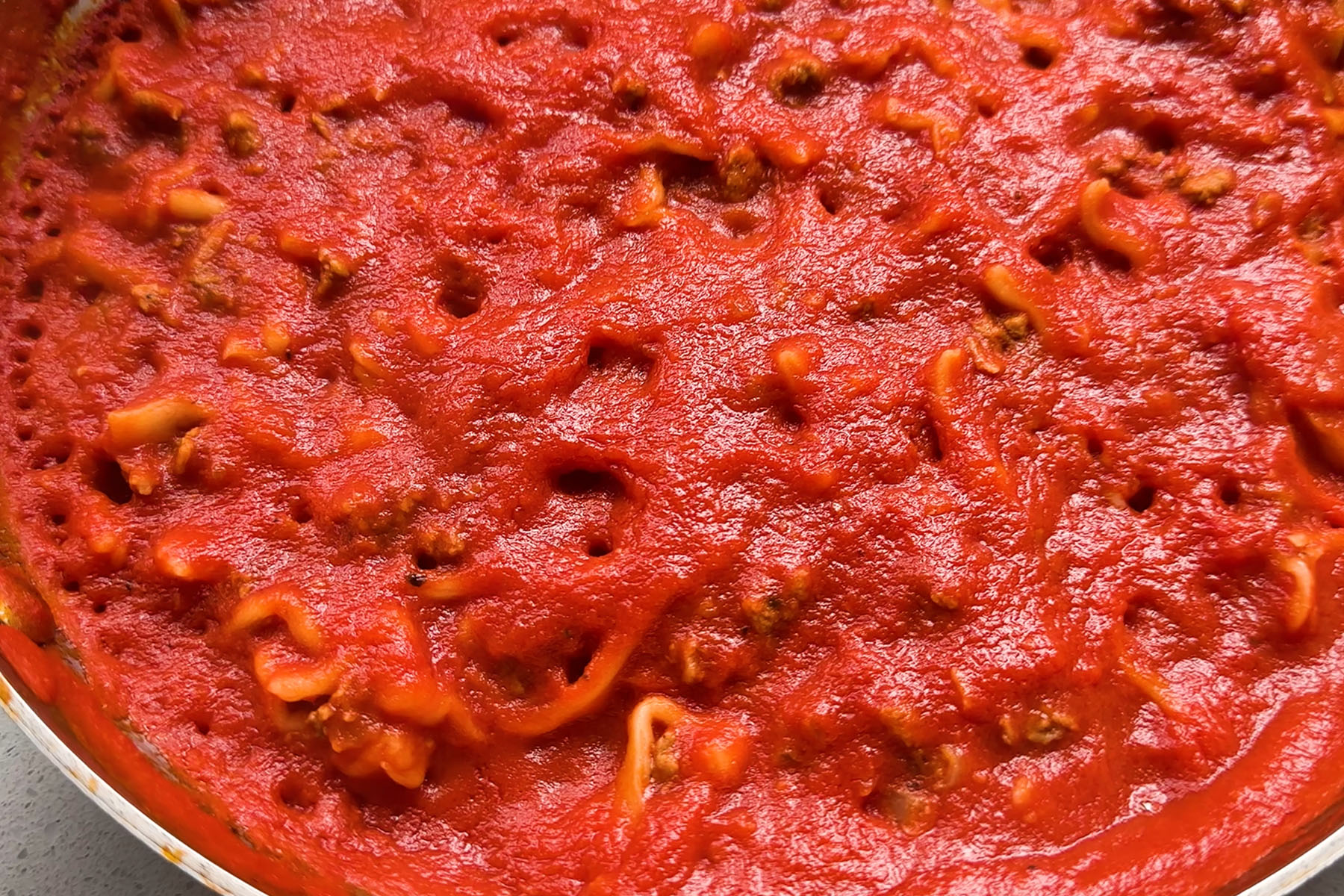 A skillet of dumplings in red sauce.
