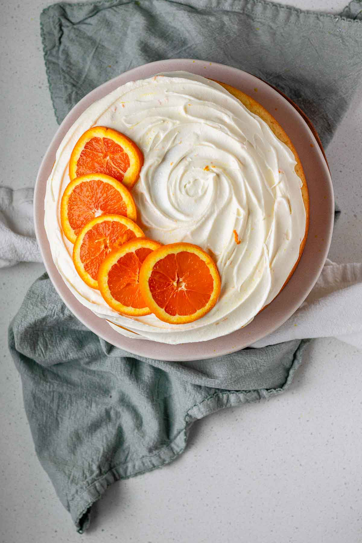 A cake with icing and orange slices on top.