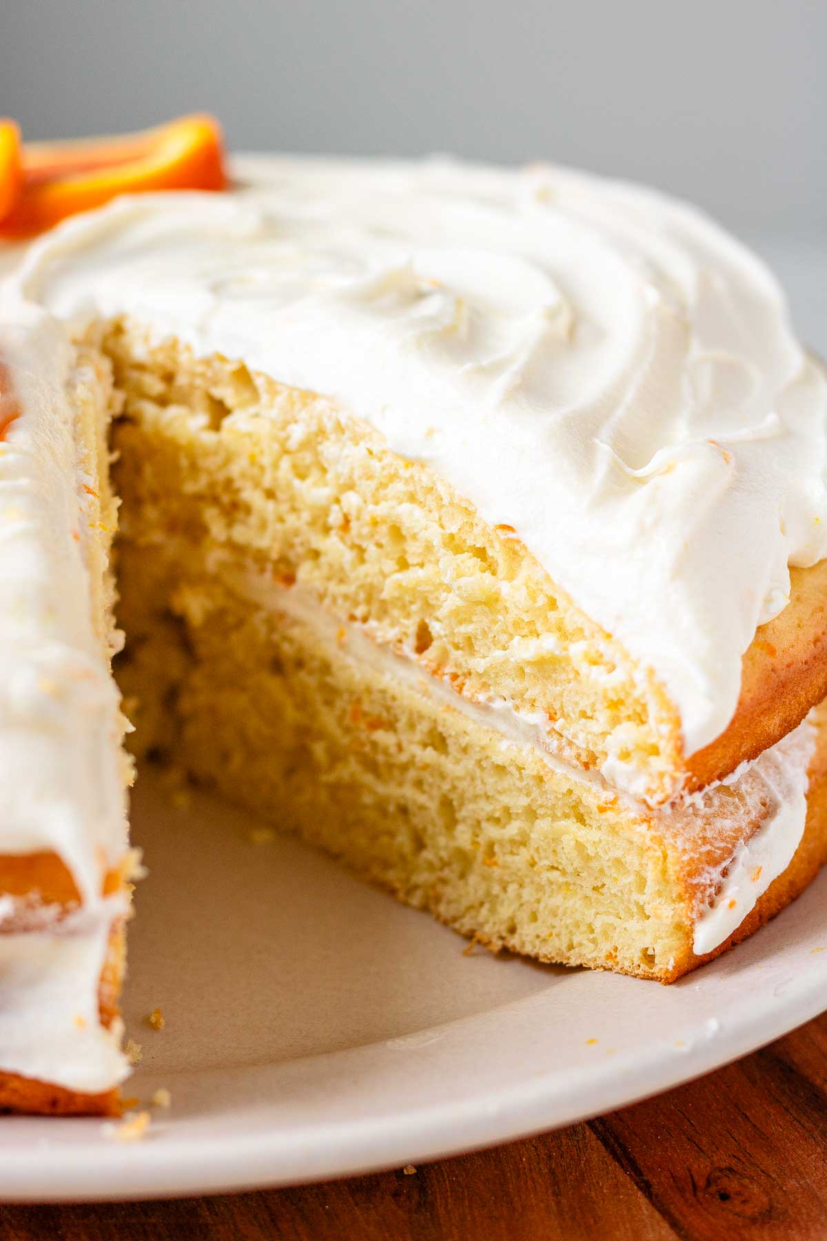 A cake with icing and orange slices on top with a slice cut out.