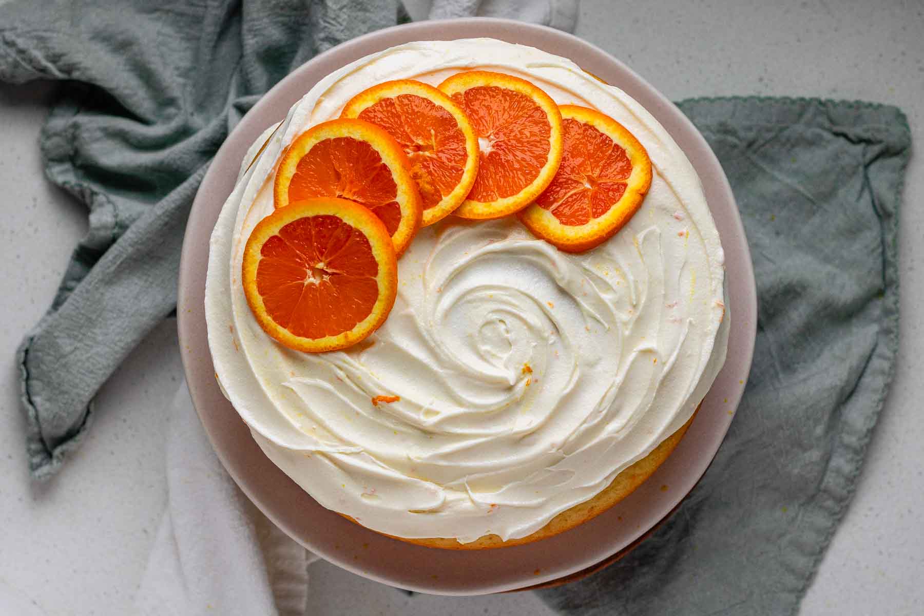 A cake with icing and orange slices on top.