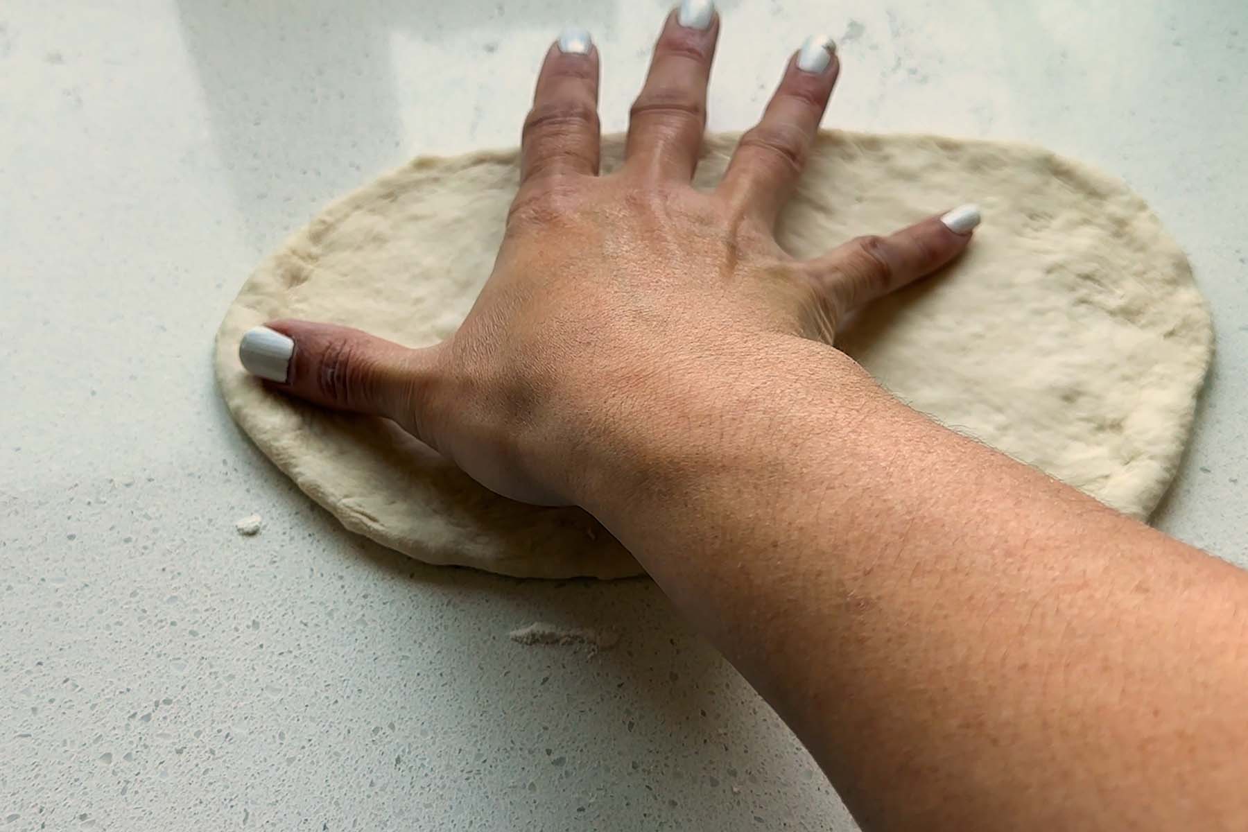 A hand measuring dough from fingertip to fingertip.