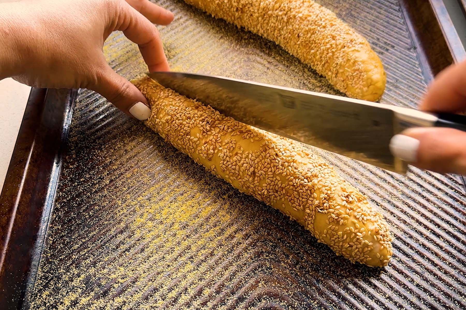A cylinder of sesame seed coated dough is sliced open.