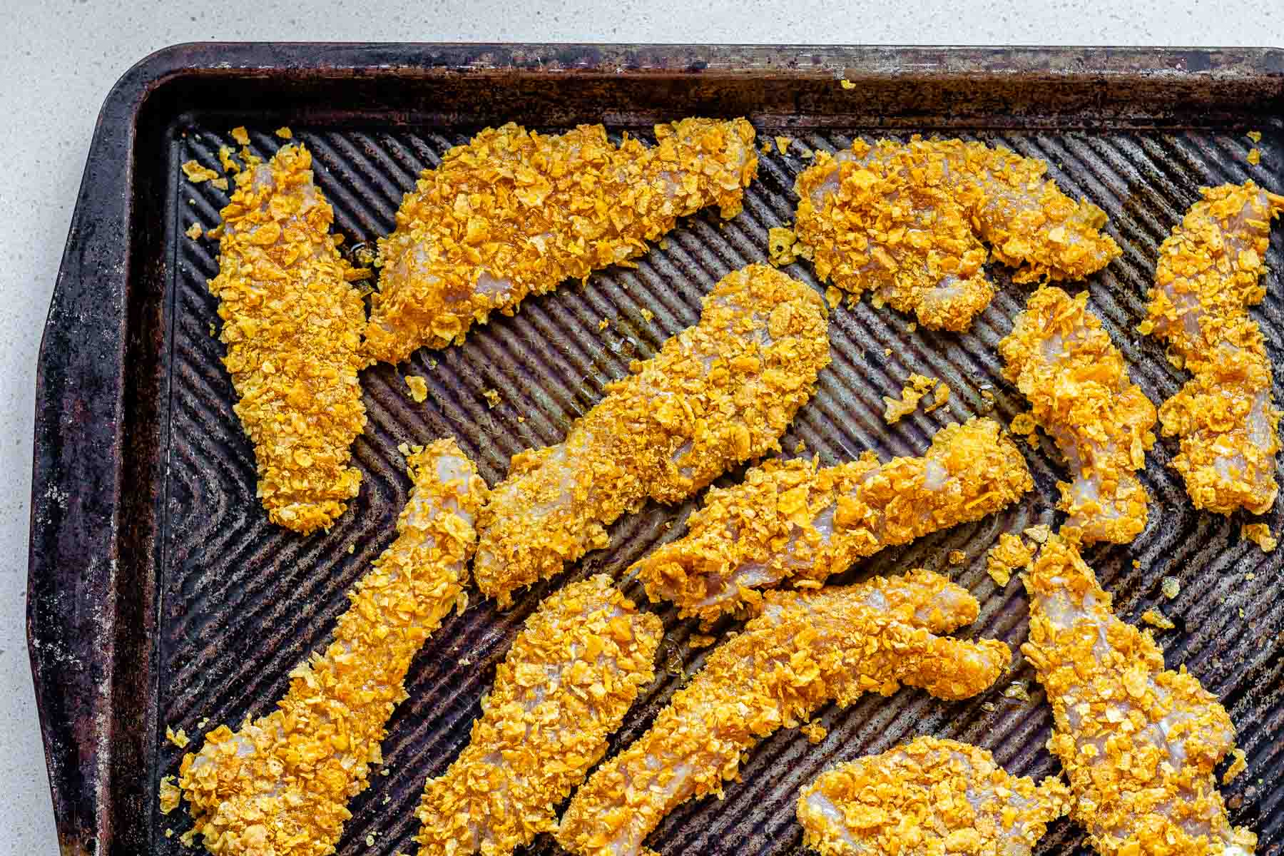 Breaded chicken strips on a baking tray.