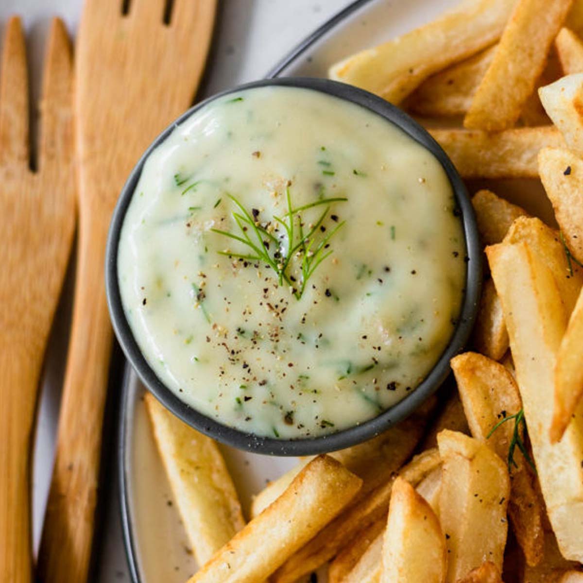 Dip in a bowl surrounded by french fries.