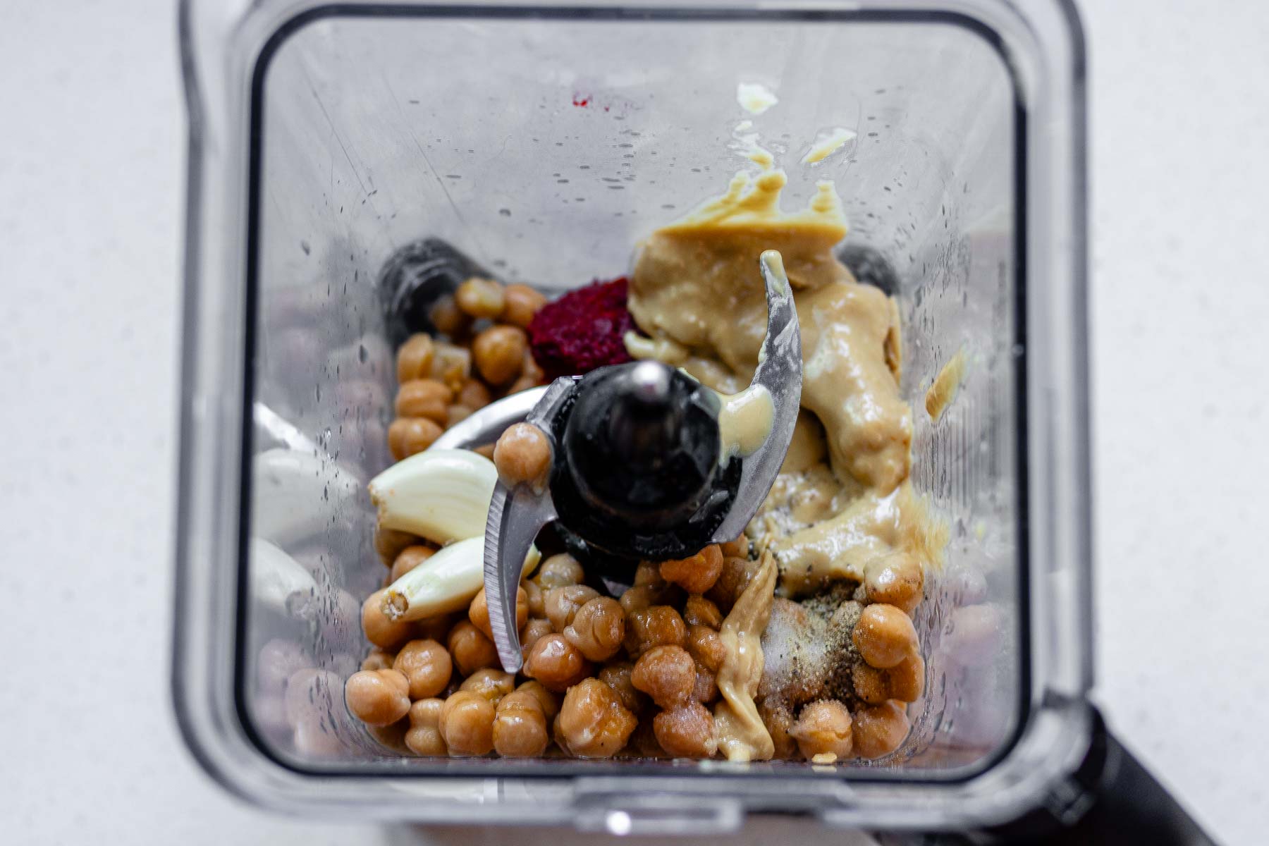 Inside look at the ingredients for hummus in a blender jar.