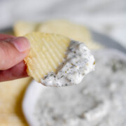 A handheld chip with a herby dip on the end of it.