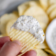 A handheld chip with a herby dip on the end of it.