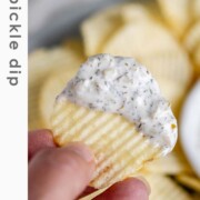 A handheld chip with a herby dip on the end of it with the text dill pickle dip.