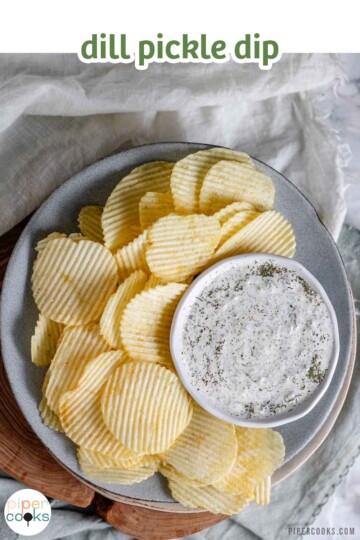 An herby dip in a bowl on a plate with chips with the text dill pickle dip.