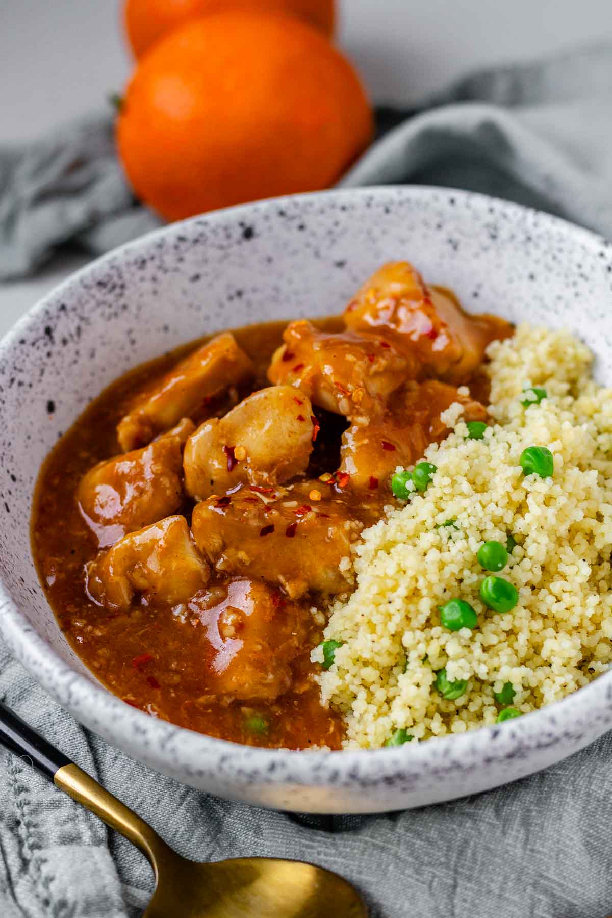 Cubed chicken in orange sauce in a bowl with couscous.