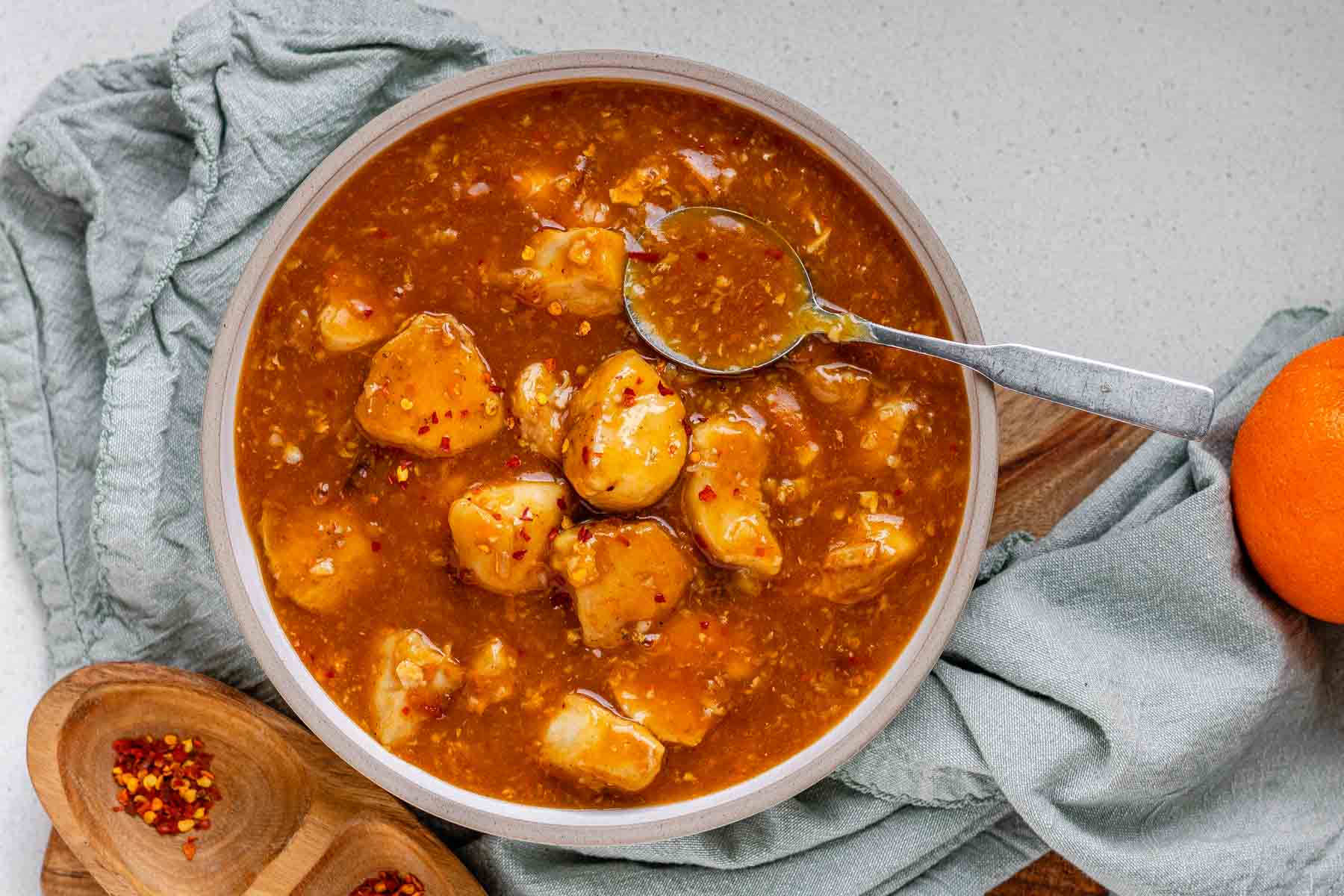 Cubed chicken in orange sauce in a bowl.