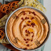 Hummus in a bowl topped with chopped sun-dried tomatoes, olive oil, and spices with the text sun-dried tomato hummus.