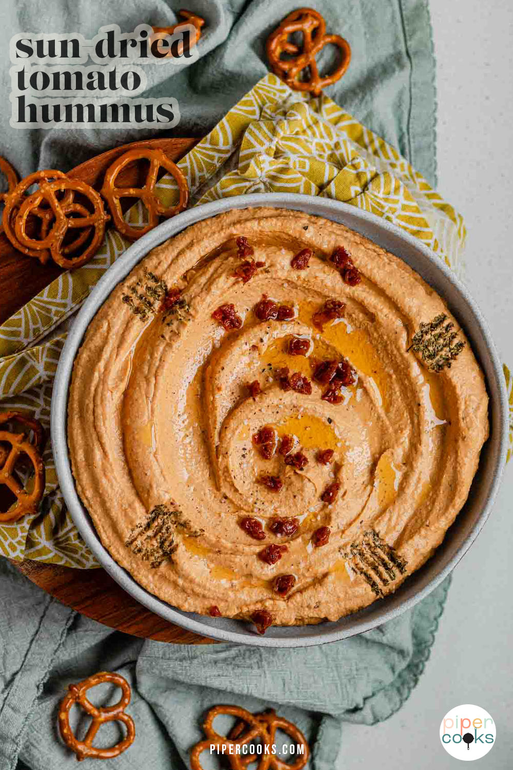 Hummus in a bowl topped with chopped sun-dried tomatoes, olive oil, and spices with the text sun-dried tomato hummus.
