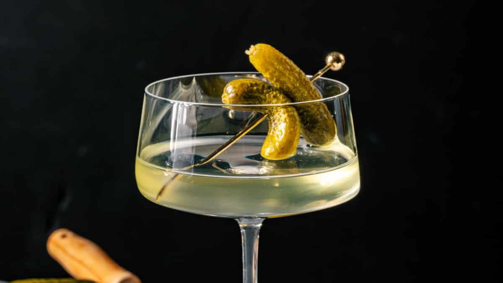 A cocktail with pickles on a cocktail stick.