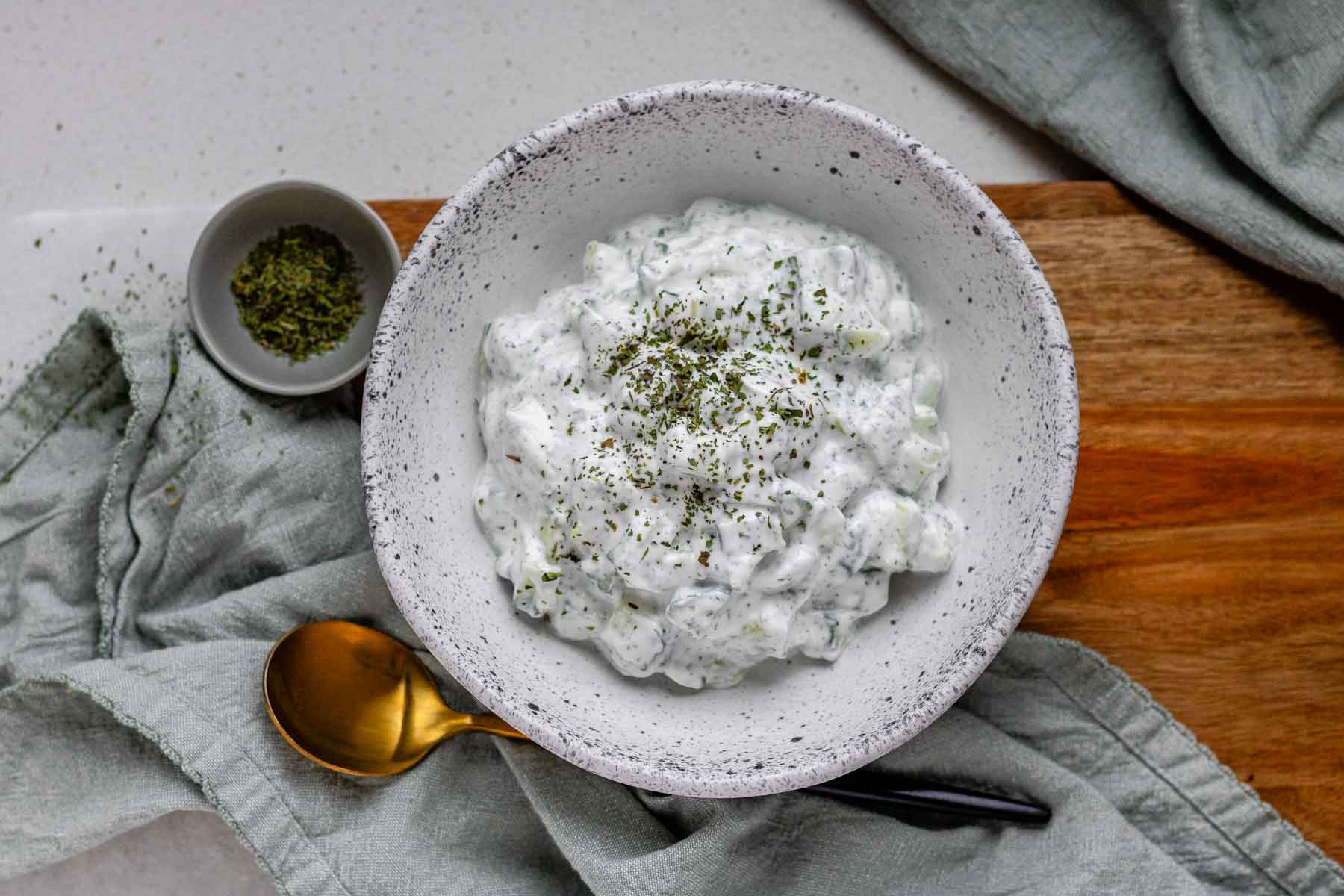 Cucumber yogurt salad in a bowl topped with dried mint.