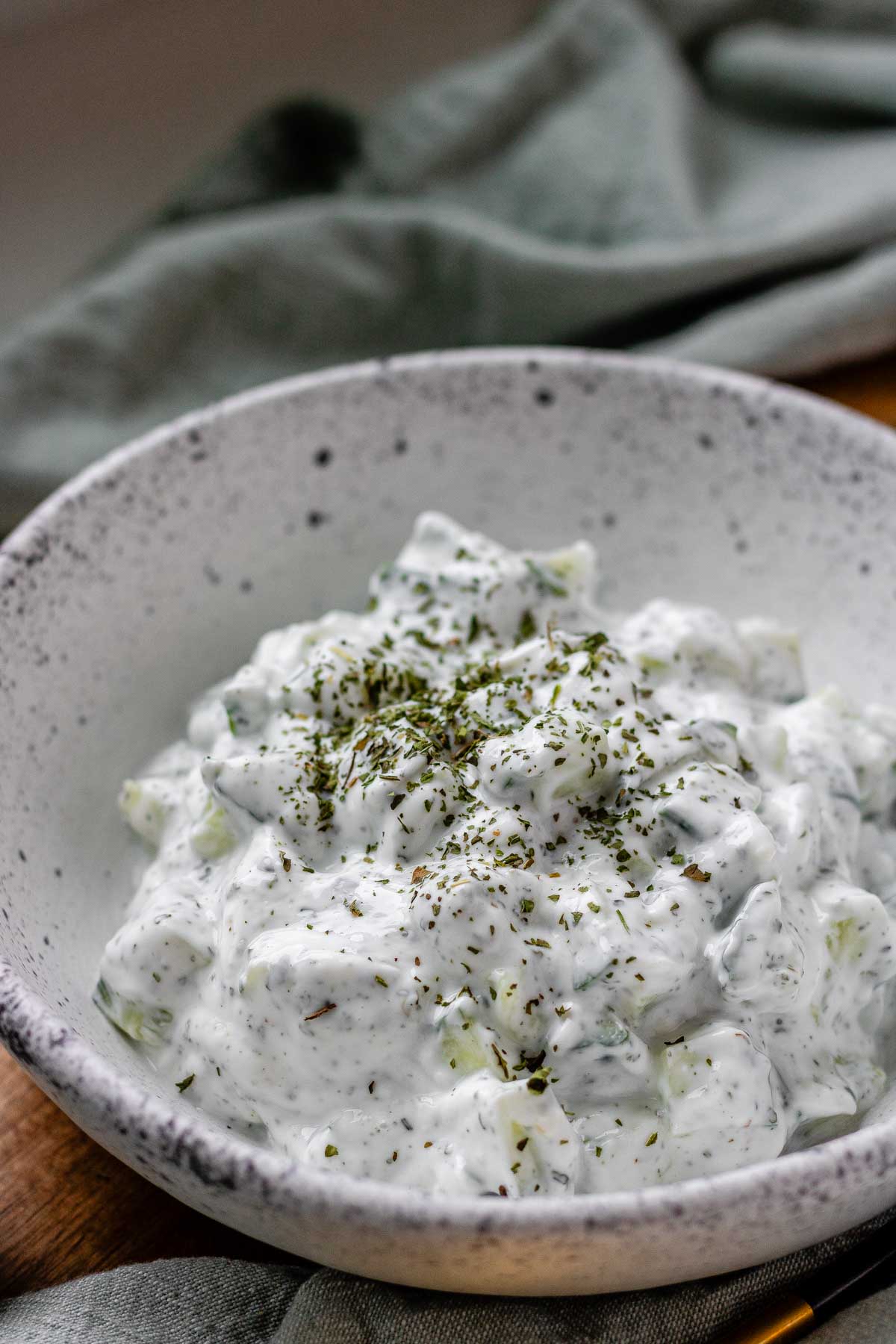 Cucumber yogurt salad in a bowl topped with dried mint.
