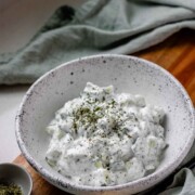 Cucumber yogurt salad in a bowl topped with dried mint with the text cucumber yogurt.