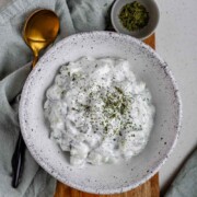Cucumber yogurt salad in a bowl topped with dried mint with the text cucumber yogurt.