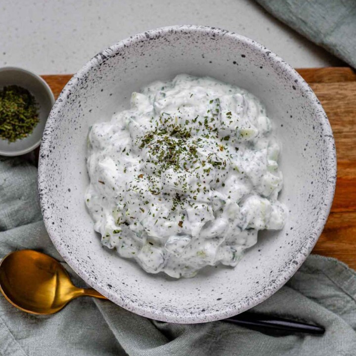Cucumber yogurt salad in a bowl topped with dried mint.
