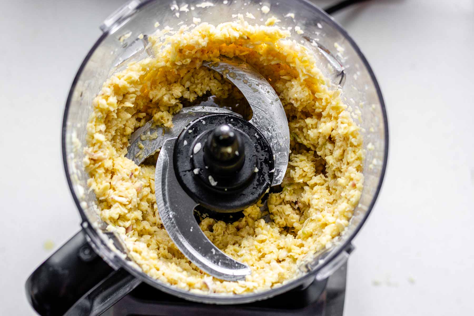 Processed garlic cloves in a food processor jar.
