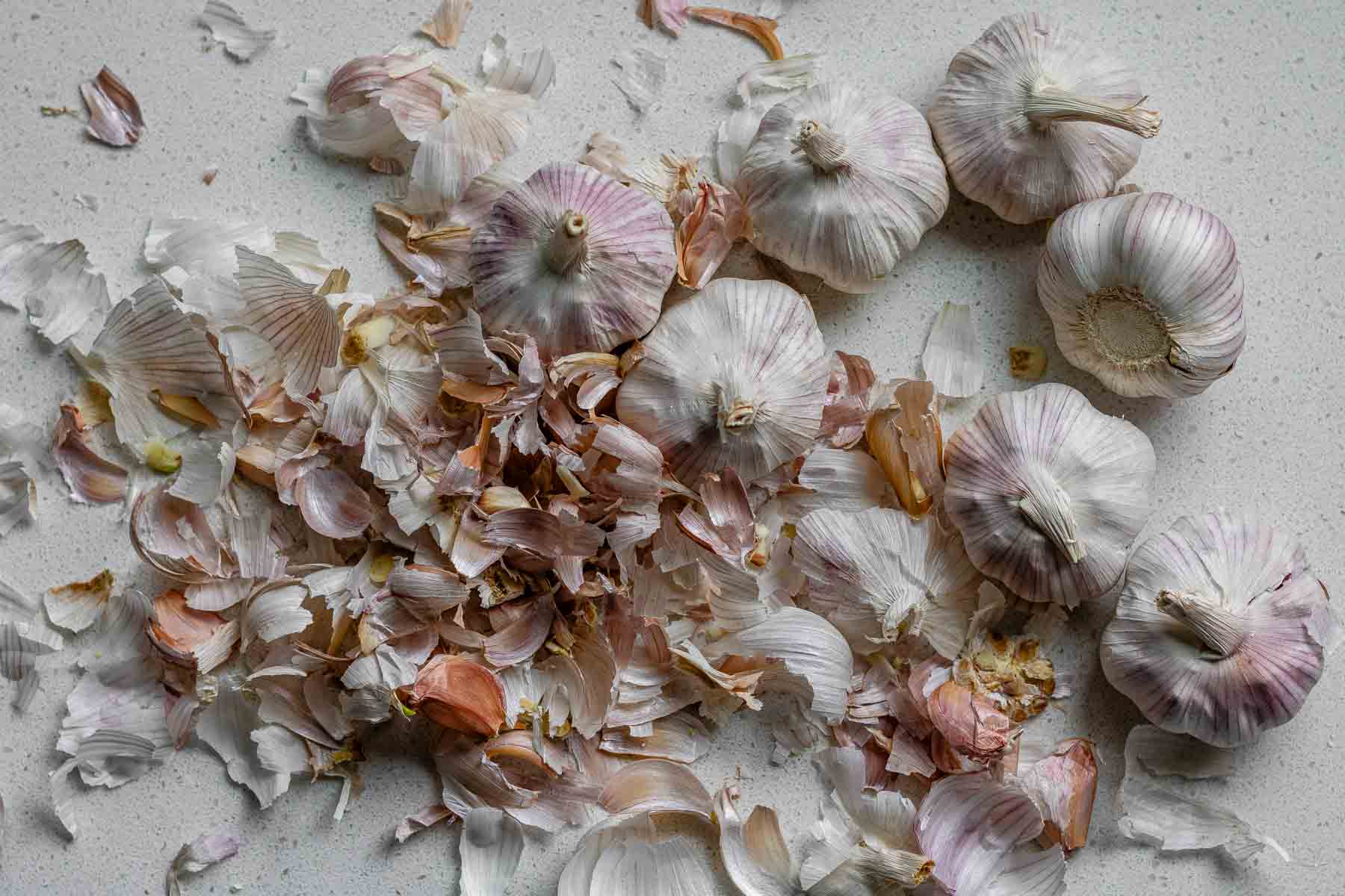 Heads of garlic surrounded by garlic peels.