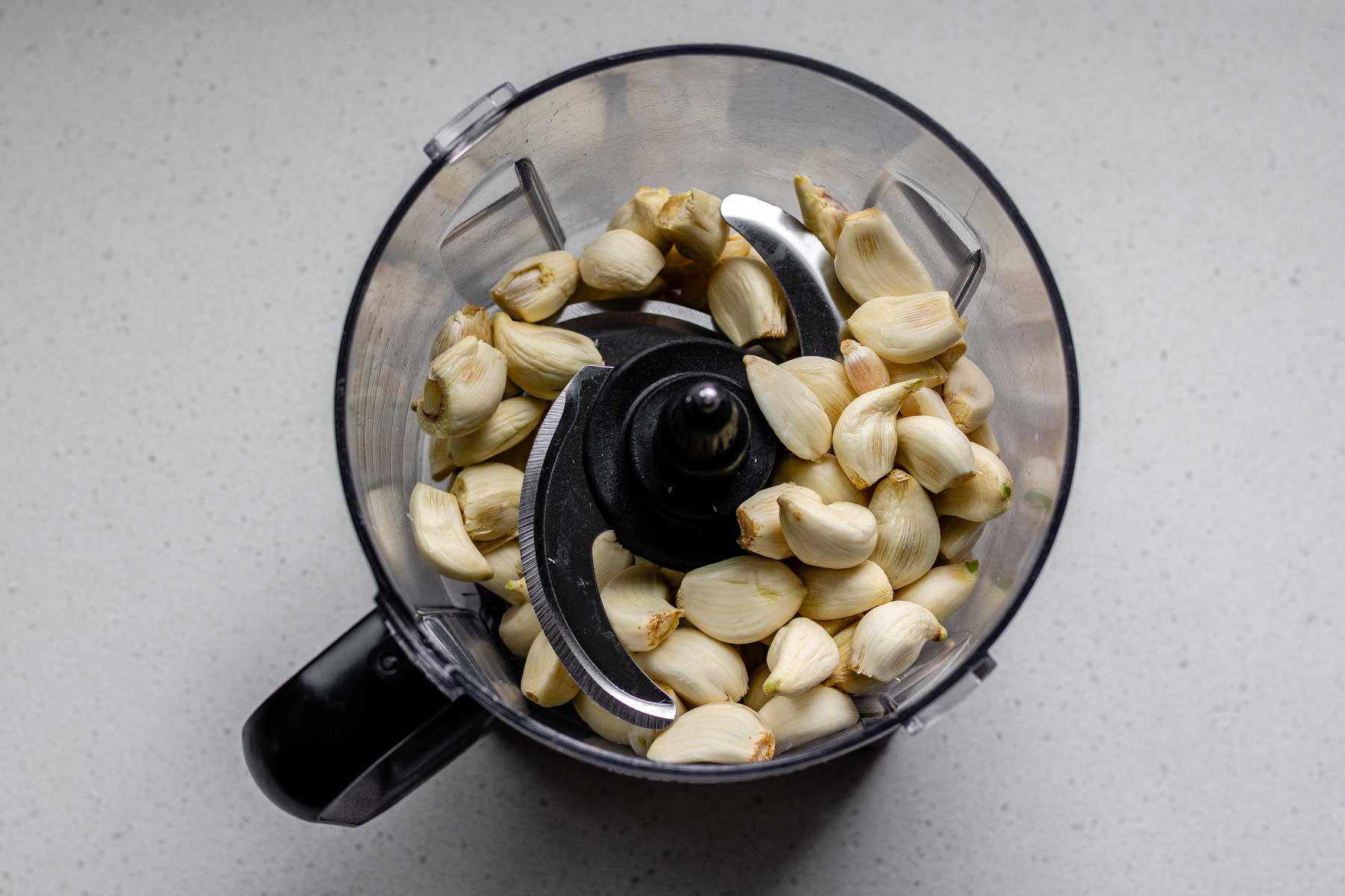 Peeled garlic cloves in a food processor jar.